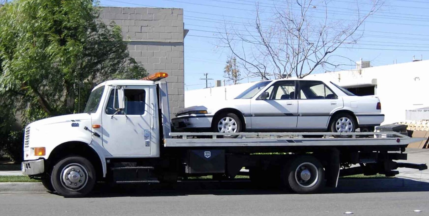 Professional flatbed towing service safely transporting sedan in Norwalk, CT